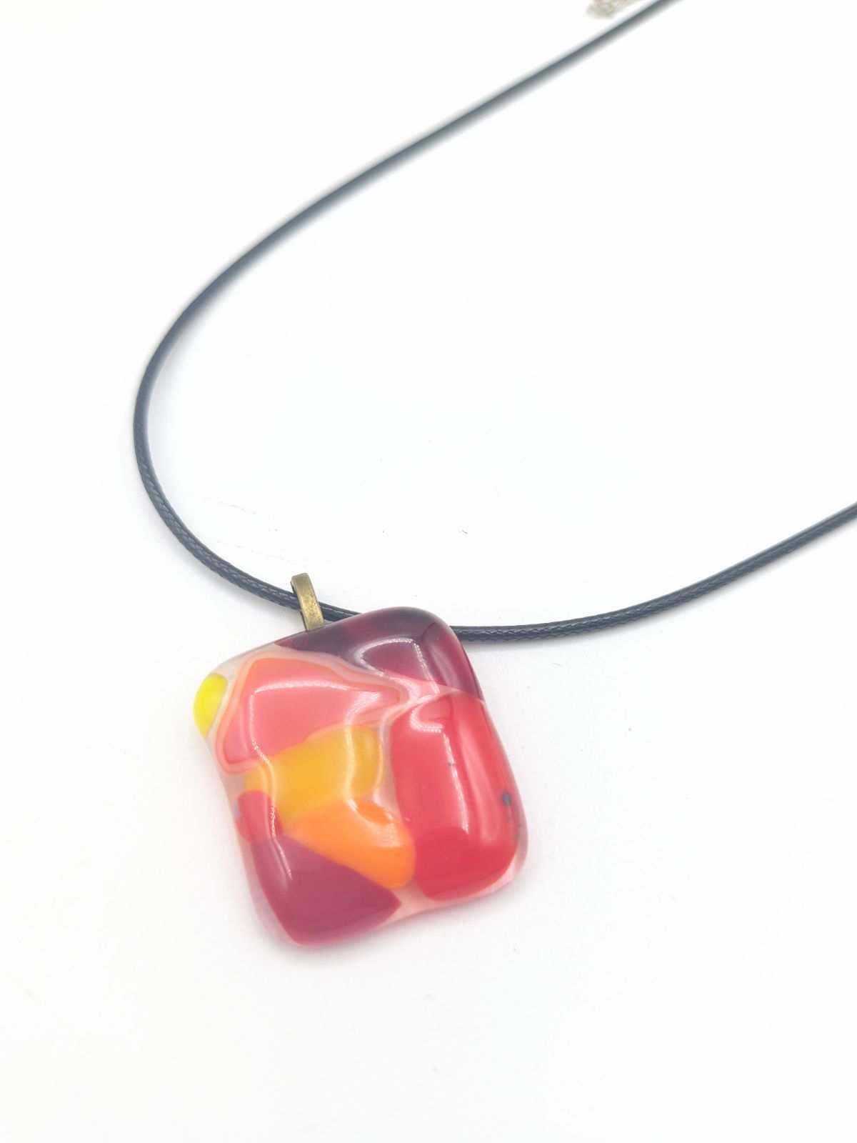 Colorful fused glass pendant necklace from Choose Your Own Fusing Project with abstract red, yellow, and pink design