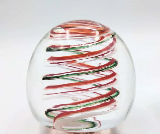 Clear glass paperweight with red and green swirling ribbons inside, handmade glass art for decoration or gift