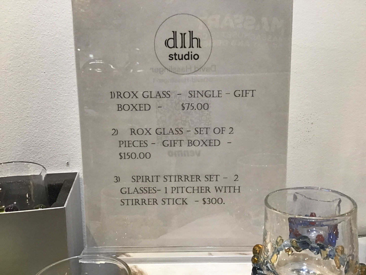 Transparent Rox Glasses with decorative beads, available individually or as gift sets, displayed alongside pricing details in a Dlh Studio sign.