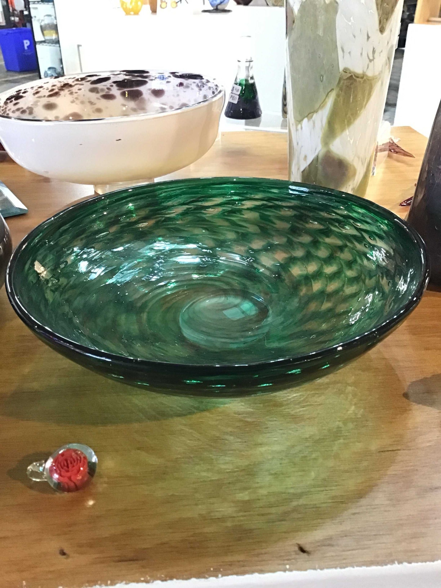 Transparent green glass bowl with textured swirl pattern on wooden surface