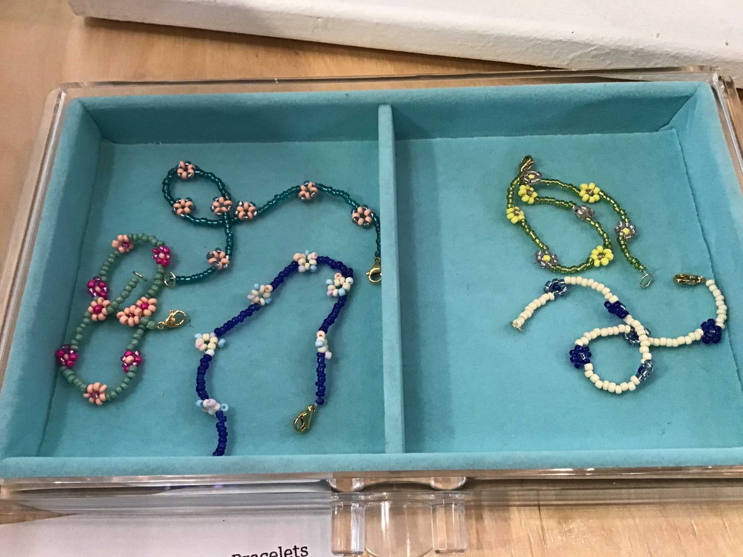 Colorful bead bracelets with flower designs in a turquoise jewelry box