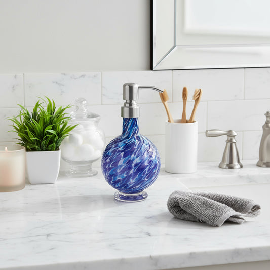 Handblown marbled glass soap dispenser in aqua and hyacinth with stainless steel pump, round textured design, shown next to a small green plant in white pot