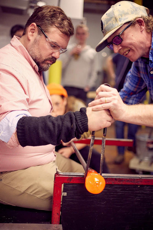 Private glassblowing demo showing professional artist shaping molten glass in studio during interactive party session