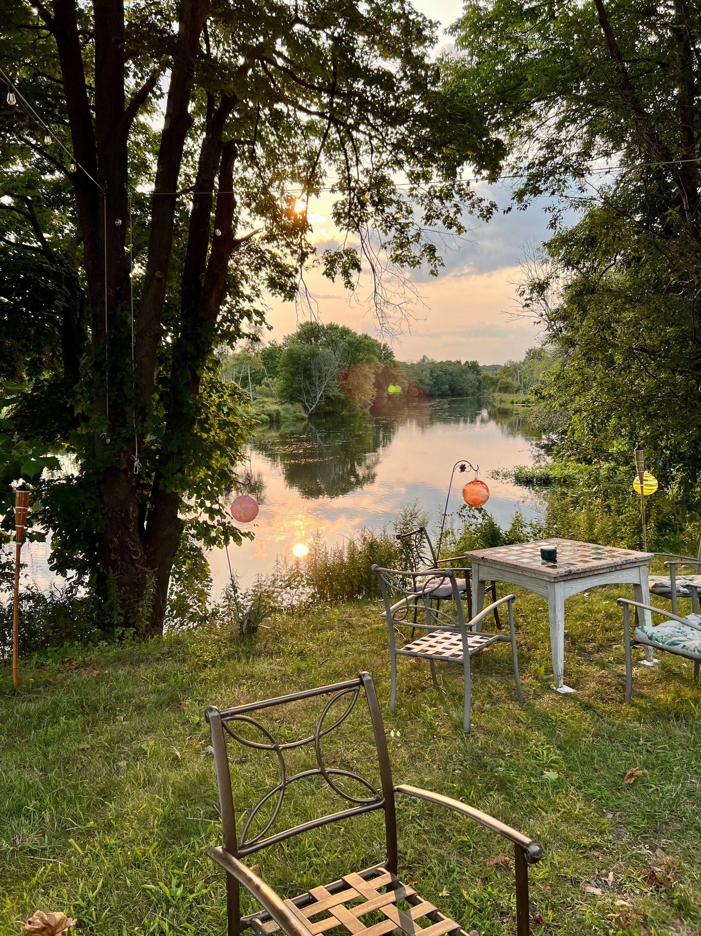 Outdoor lakeside seating area with metal chairs and table at sunset for Date Night Glassblowing event