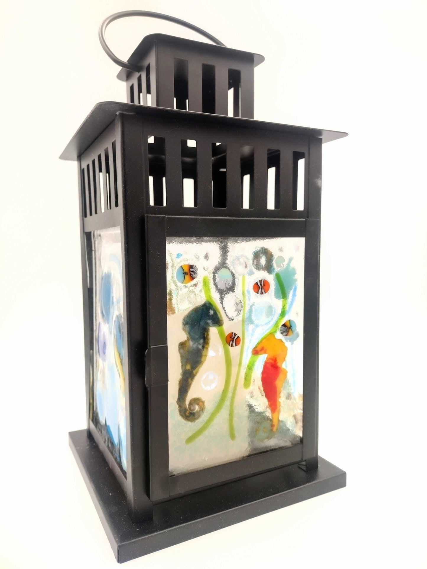 Black metal lantern with colorful fused glass panels featuring sea creatures and abstract designs.
