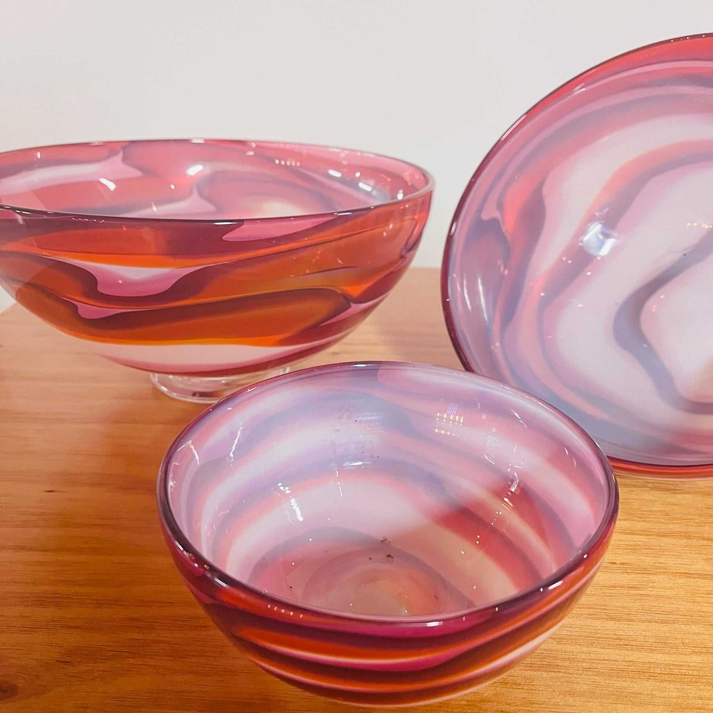 Set of three hand blown glass bowls with swirling red, orange, and white lava wave patterns, perfect as decorative centerpieces.