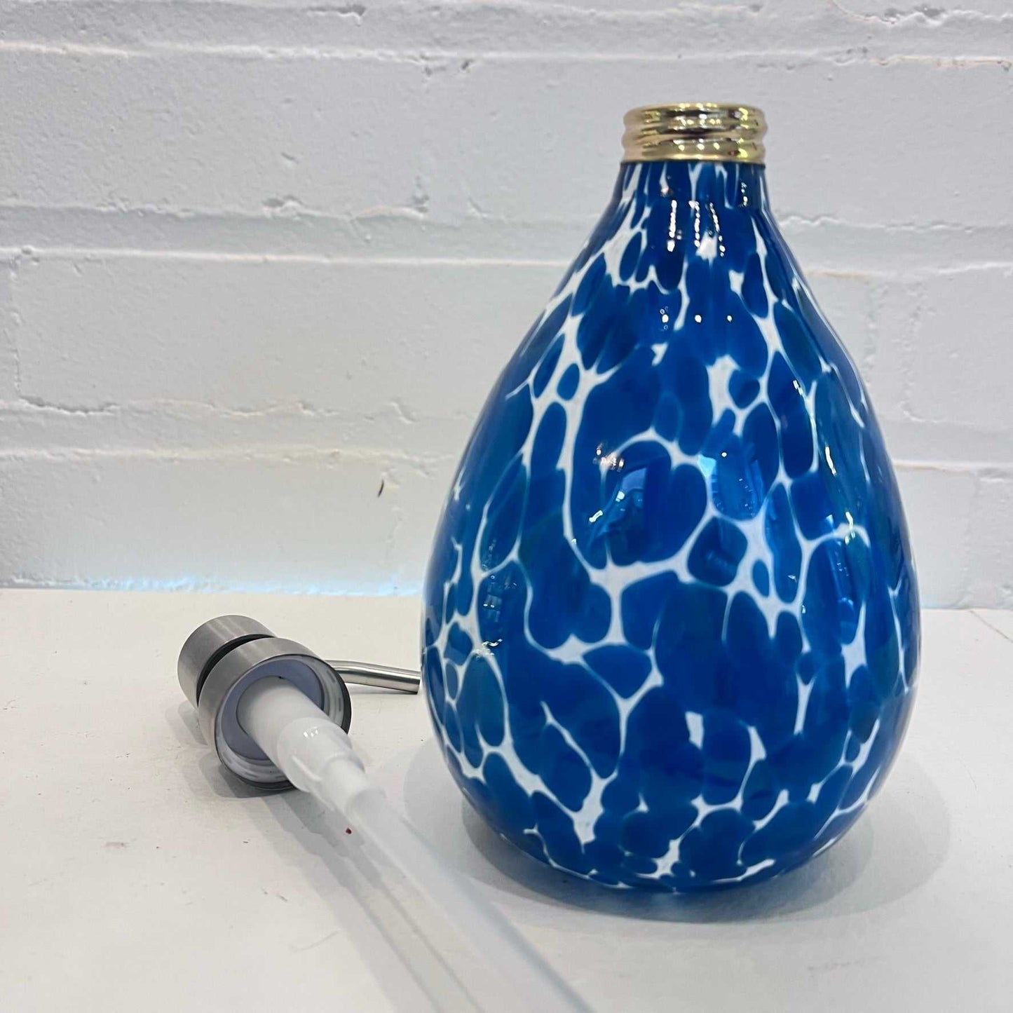 Bluestone Soap Dispenser with blue and white speckled design and separate pump mechanism on a white surface against a white brick wall background