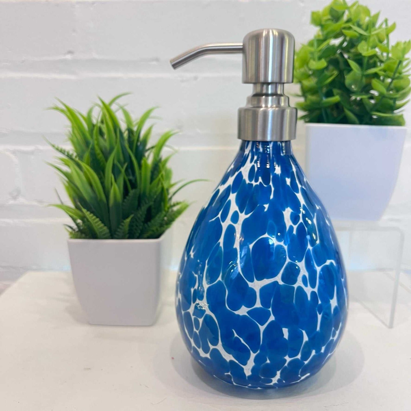 Bluestone Soap Dispenser with blue and white pattern and stainless steel pump next to green plants