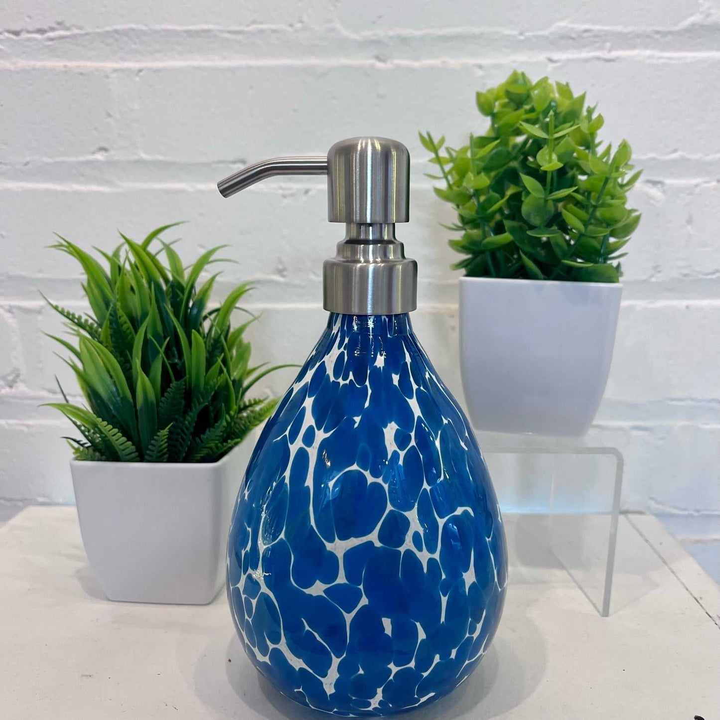 Bluestone soap dispenser with blue and white marbled design and stainless steel pump next to green plants