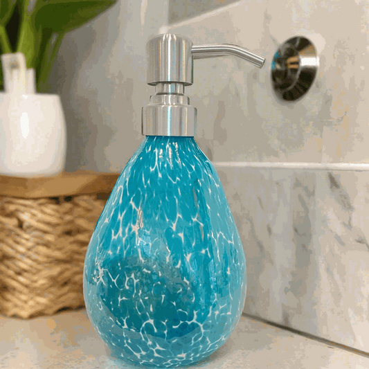 Hand blown glass teal speckled soap dispenser with silver pump on bathroom counter