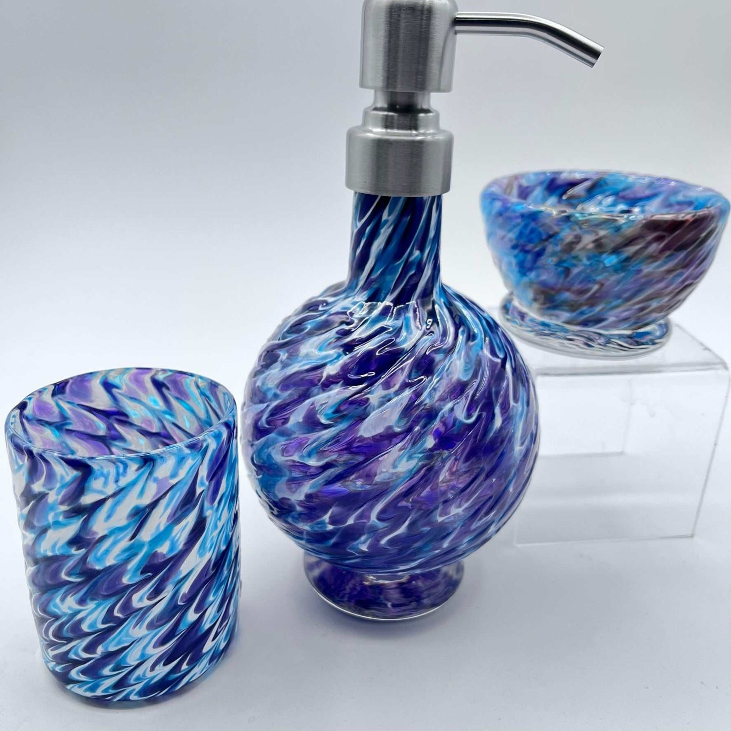 Handmade marbled glass vanity set in hyacinth and aqua with soap dispenser, bowl, and glass.