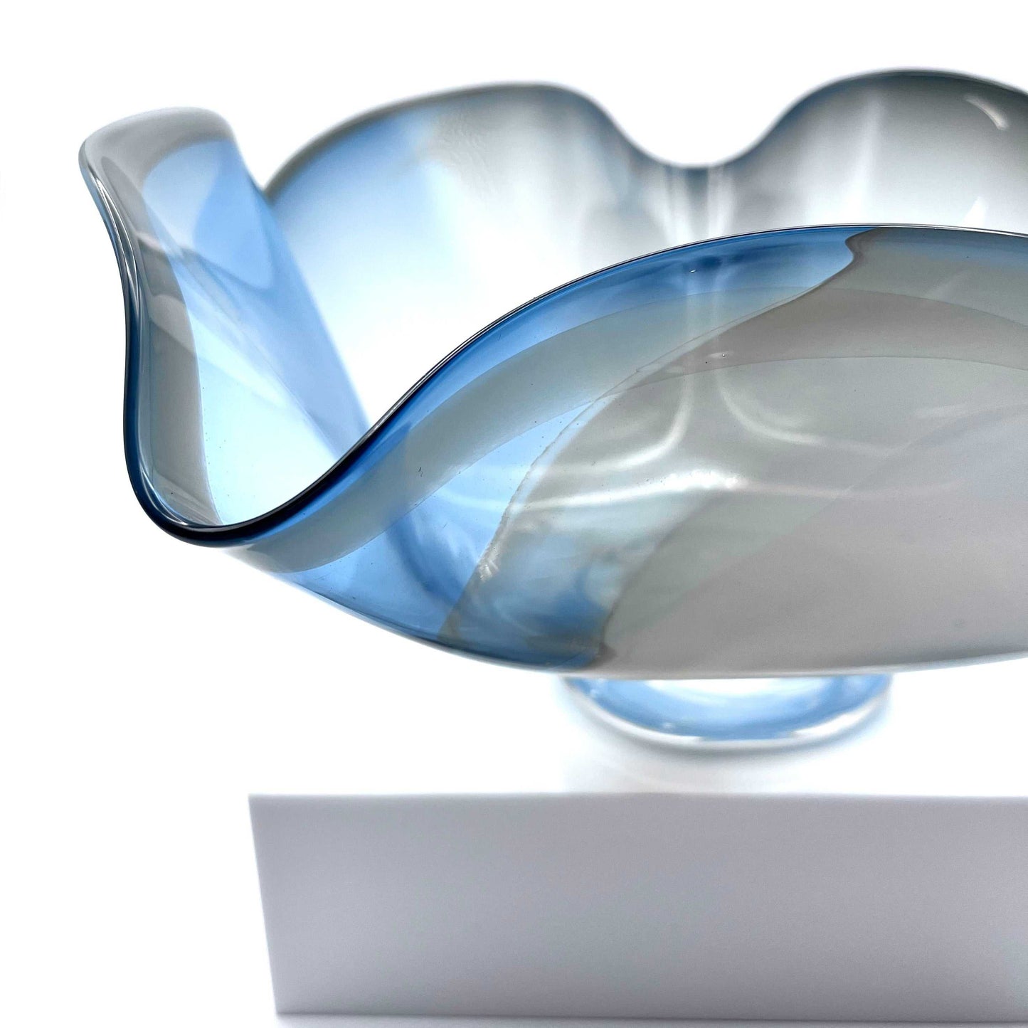 Handcrafted blue and white twisted glass bowl shaped from hot glass with wavy edges