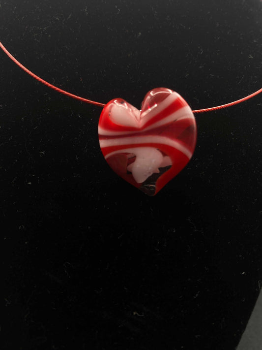 Red and white striped heart-shaped glass pendant on a thin red wire for private group glass experience craft session