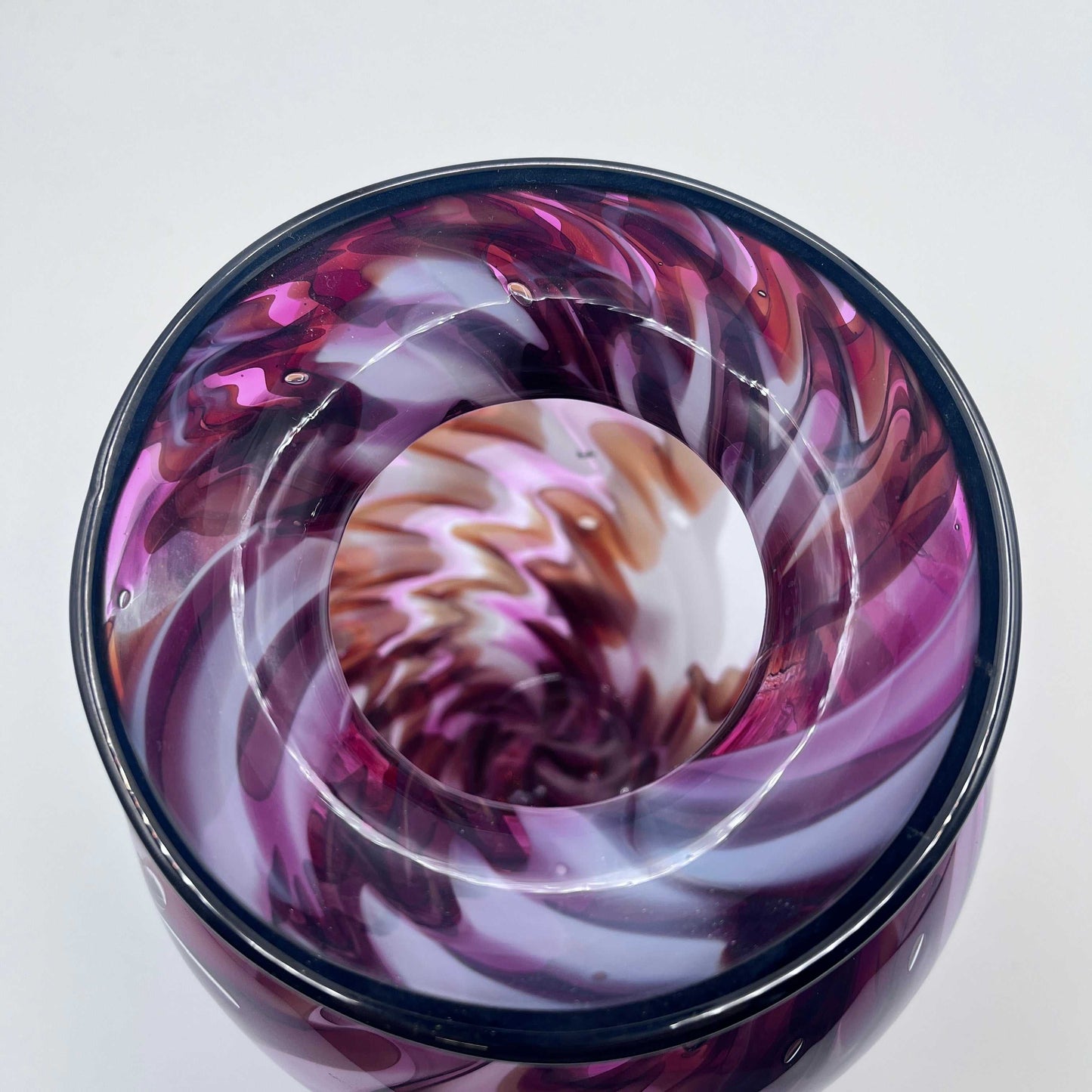 Top view of a hand blown lava vase with swirling purple, white, and brown patterns in glass