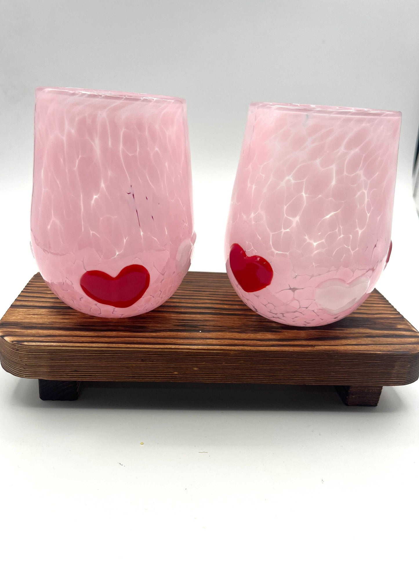 Pair of handmade pink Love Cups stemless wine glasses with red and white heart accents on wooden stand