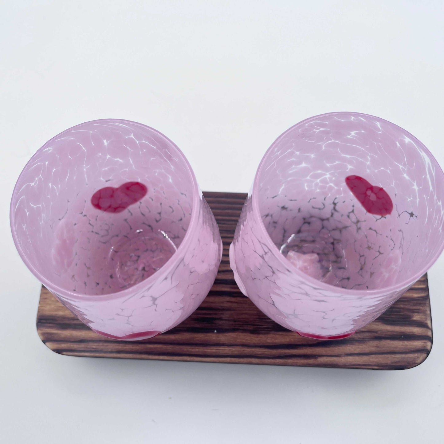Pair of hand-blown pink Love Cups stemless wine glasses with heart accents on a wooden tray