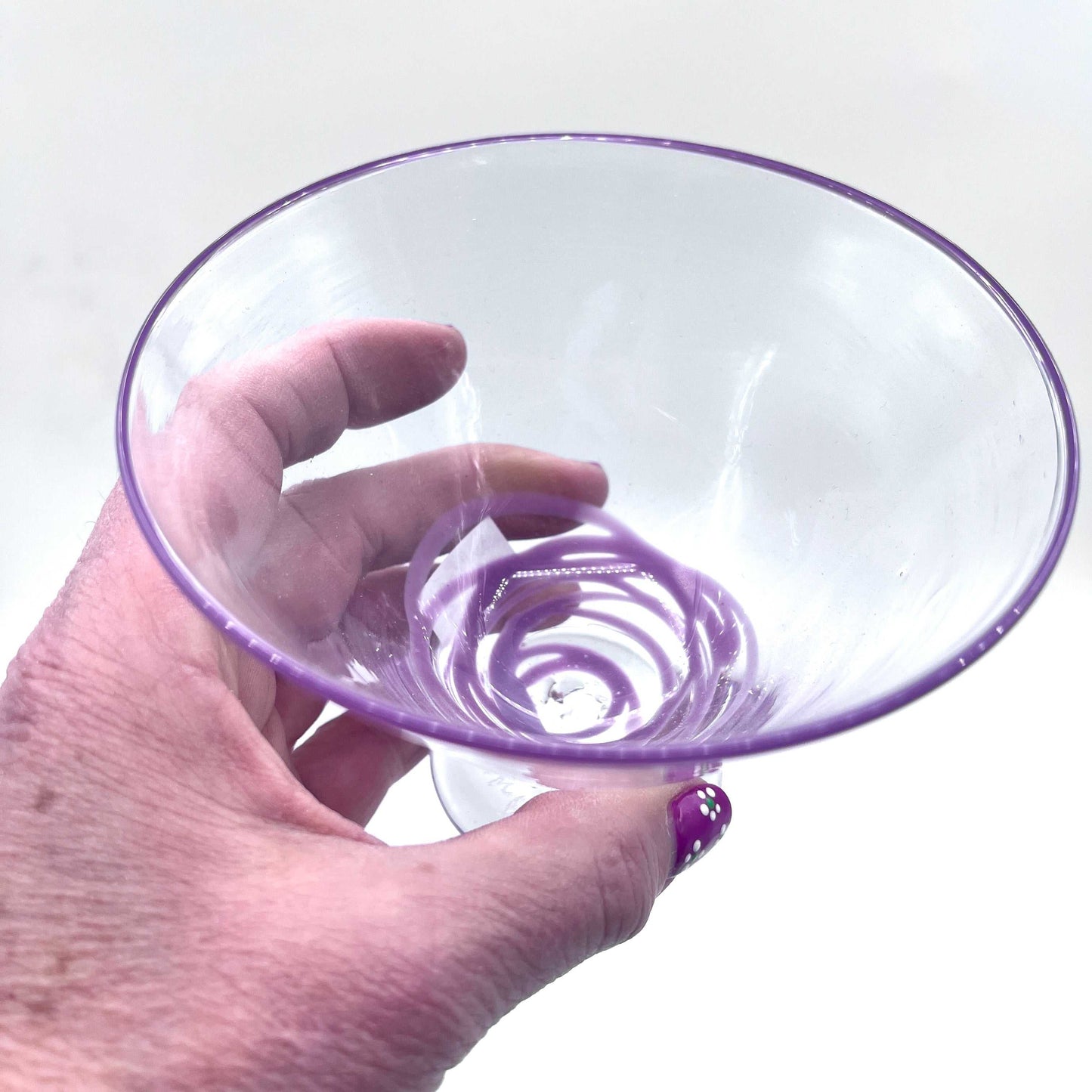 Hand blown stemless martini glass with purple rim held in hand, artisan crafted and unique design