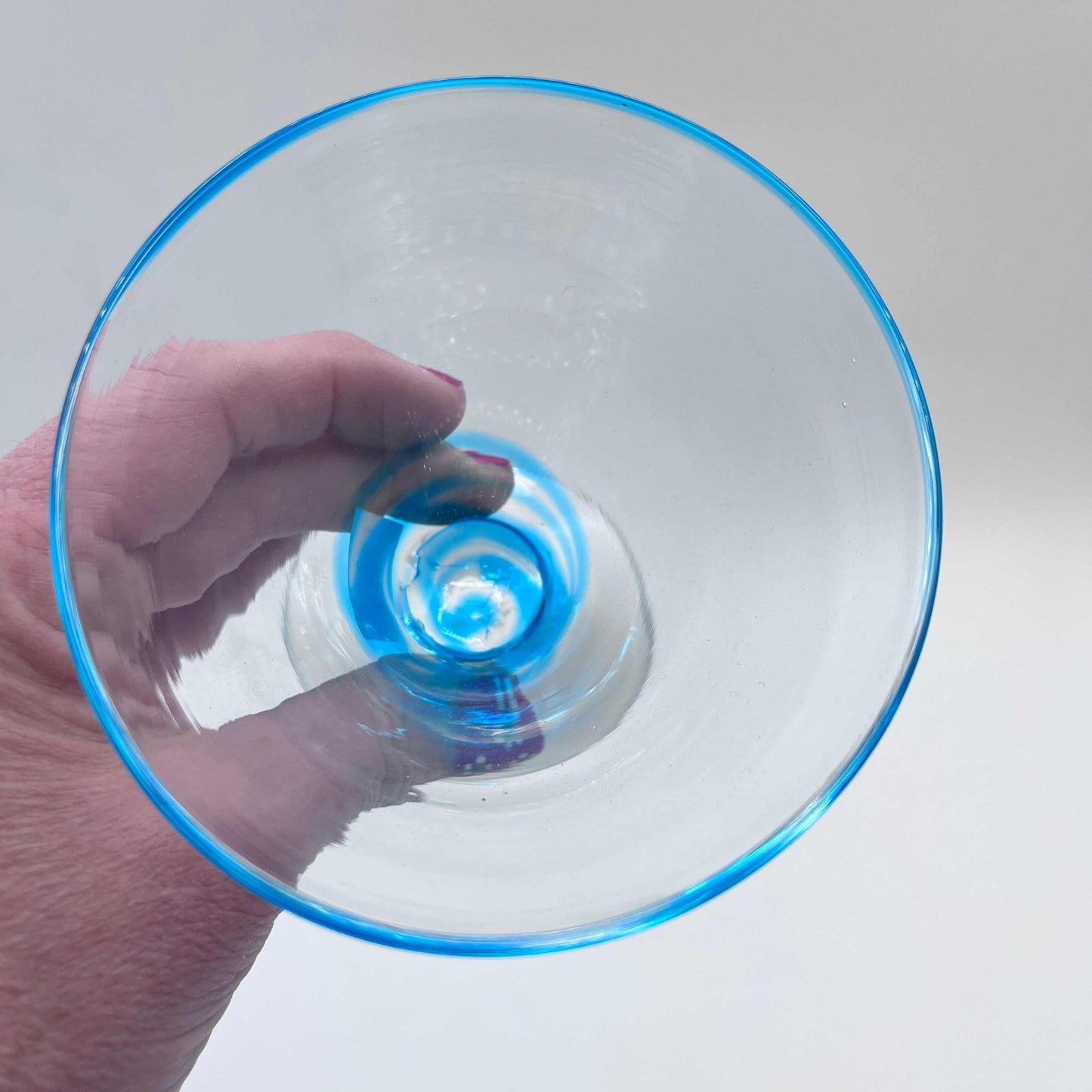 Hand blown stemless martini glass with blue rim, artisan crafted and unique design, 10-ounce capacity.