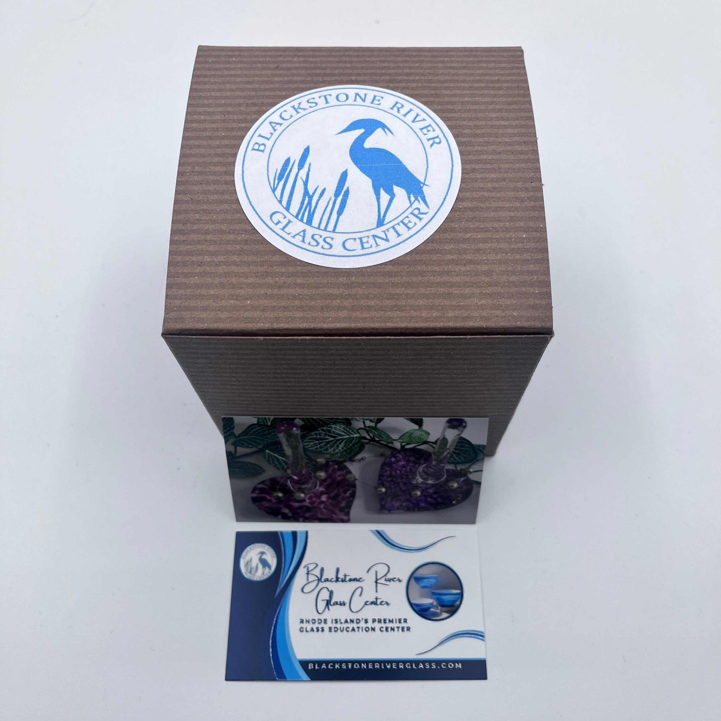 Brown packaging box with Blackstone River Glass Center logo and business card for glass art education center