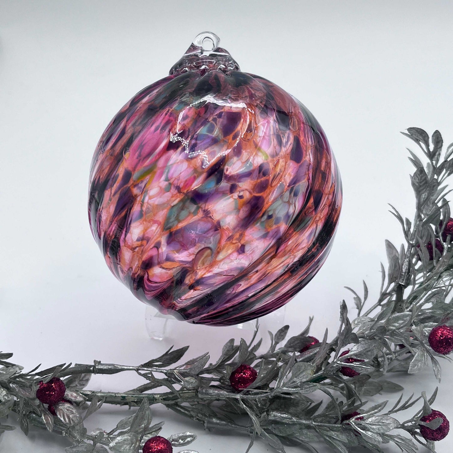Handcrafted blown glass ornament with vibrant sunset spiral twist design, perfect for holiday decoration or gifting