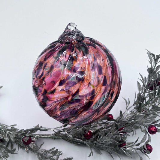 Handcrafted blown glass ornament with vibrant sunset spiral twist design, perfect for holiday decoration or gift.