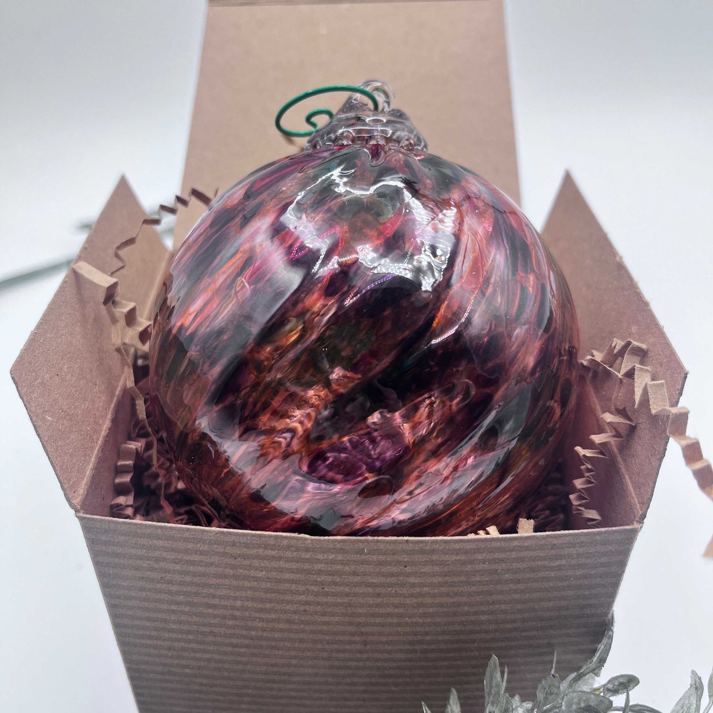 Hand blown Sunset Spiral Twist glass ornament in gift box with red and black swirls
