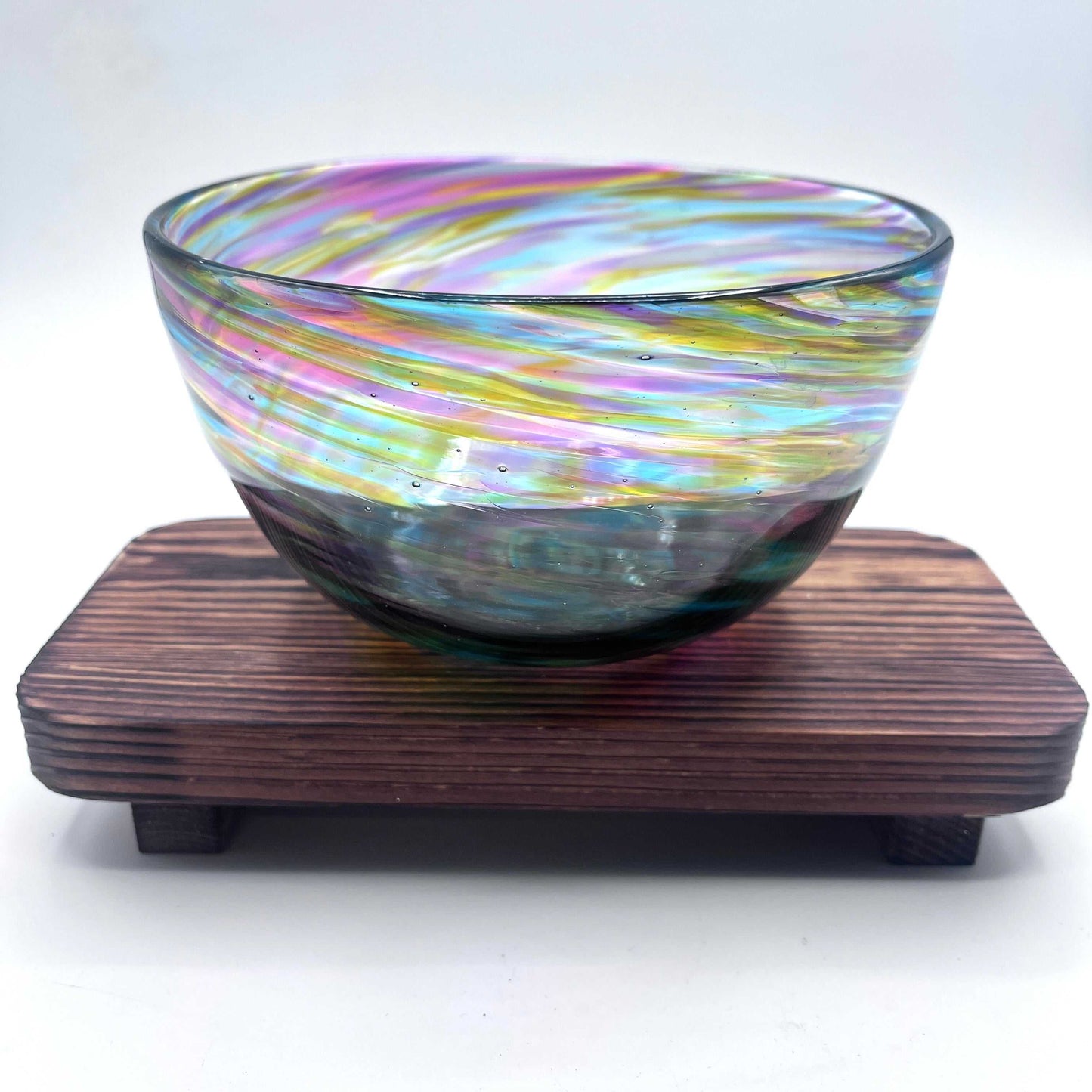 Hand-blown Rainbow Twist Serving Bowl with vibrant rainbow gradient colors and twisting design on wooden stand