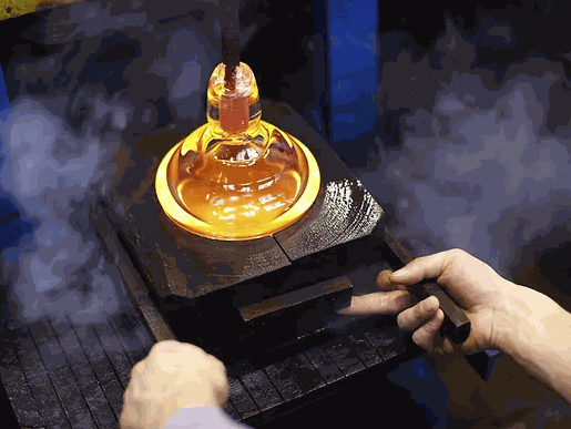 Hands shaping molten glass during a Happy Hour Glass Blowing session with glowing orange glass and tools.
