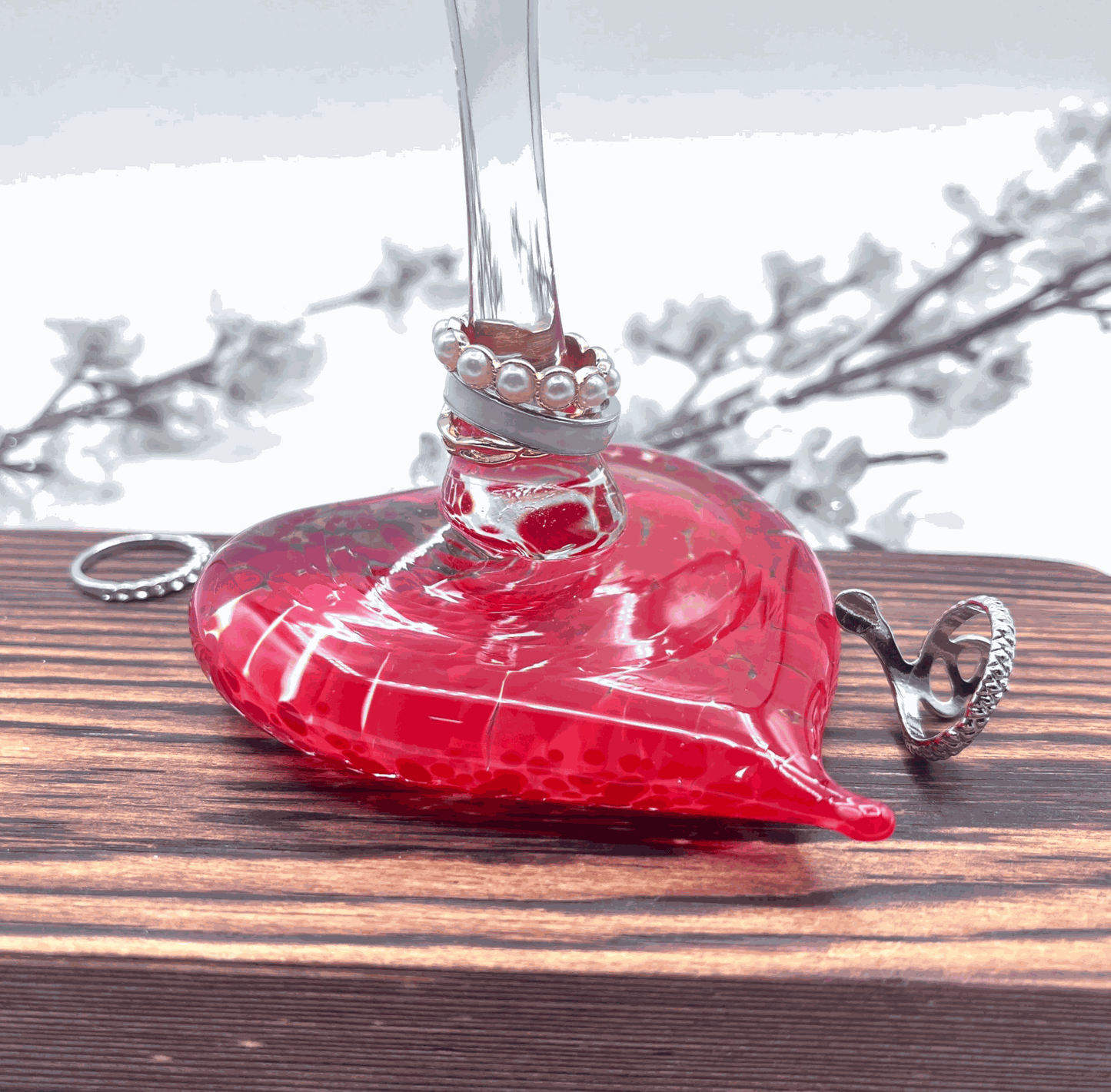 Hand-blown Ferrari red glass heart ring stand and jewelry holder on wooden surface with rings displayed