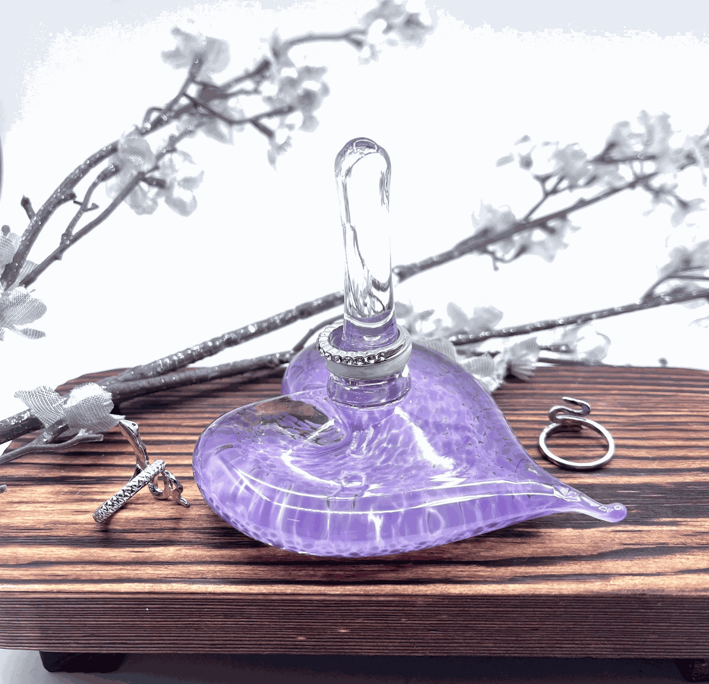 Lavender hand-blown glass heart ring stand and jewelry holder on wooden surface with rings and decorative branches