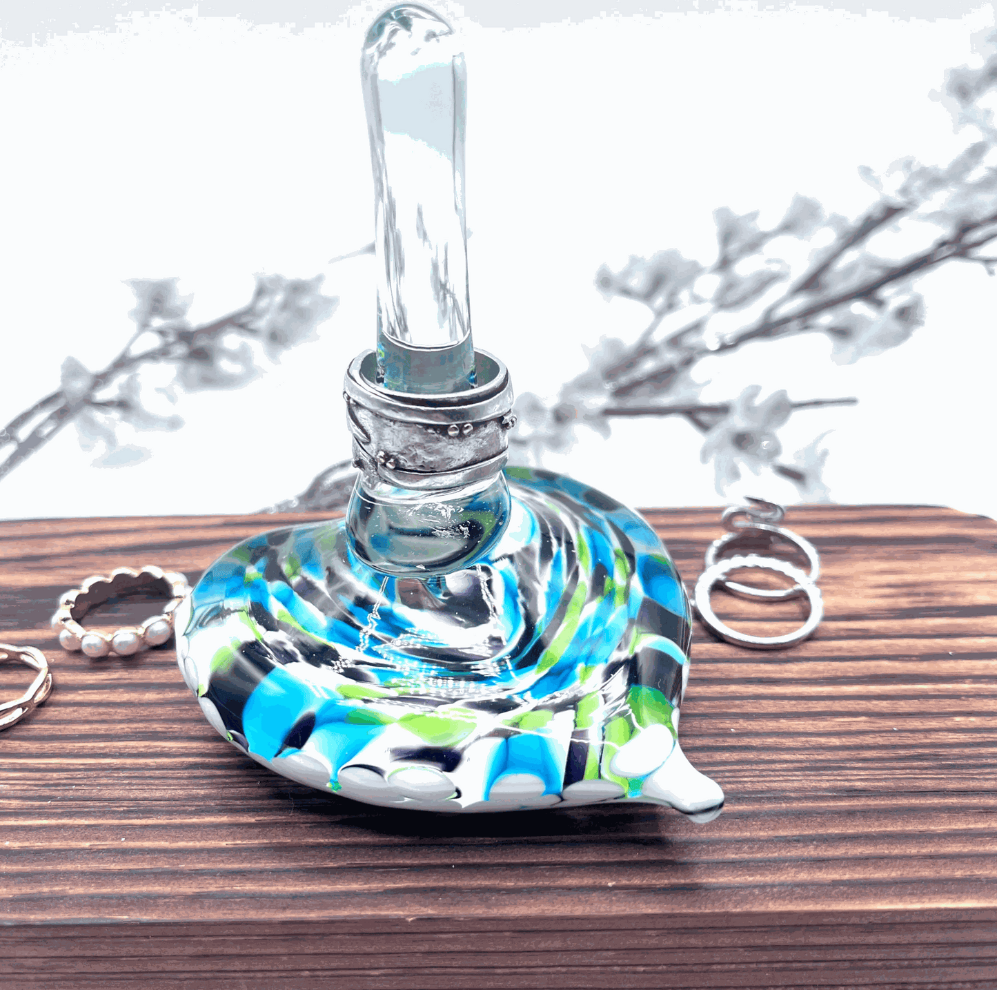 Hand-blown glass heart ring stand with jewel-tone swirls, designed for holding rings and small jewelry on a wooden surface.