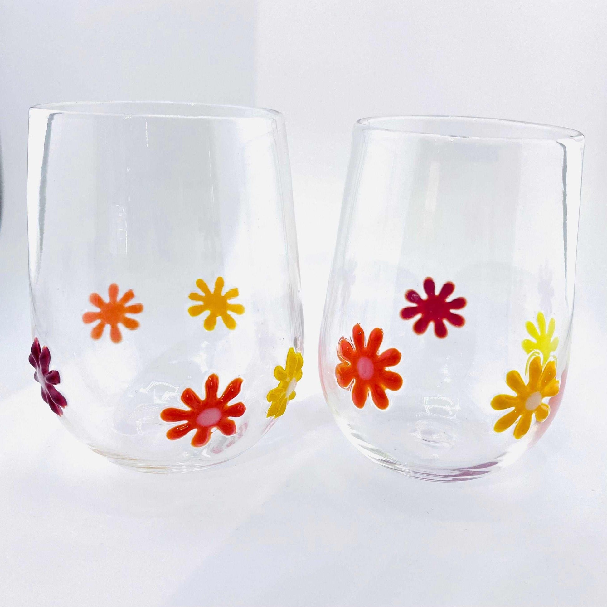 Flower Power stemless wine glasses with colorful hand-blown glass flowers, 12 oz capacity, dishwasher safe.