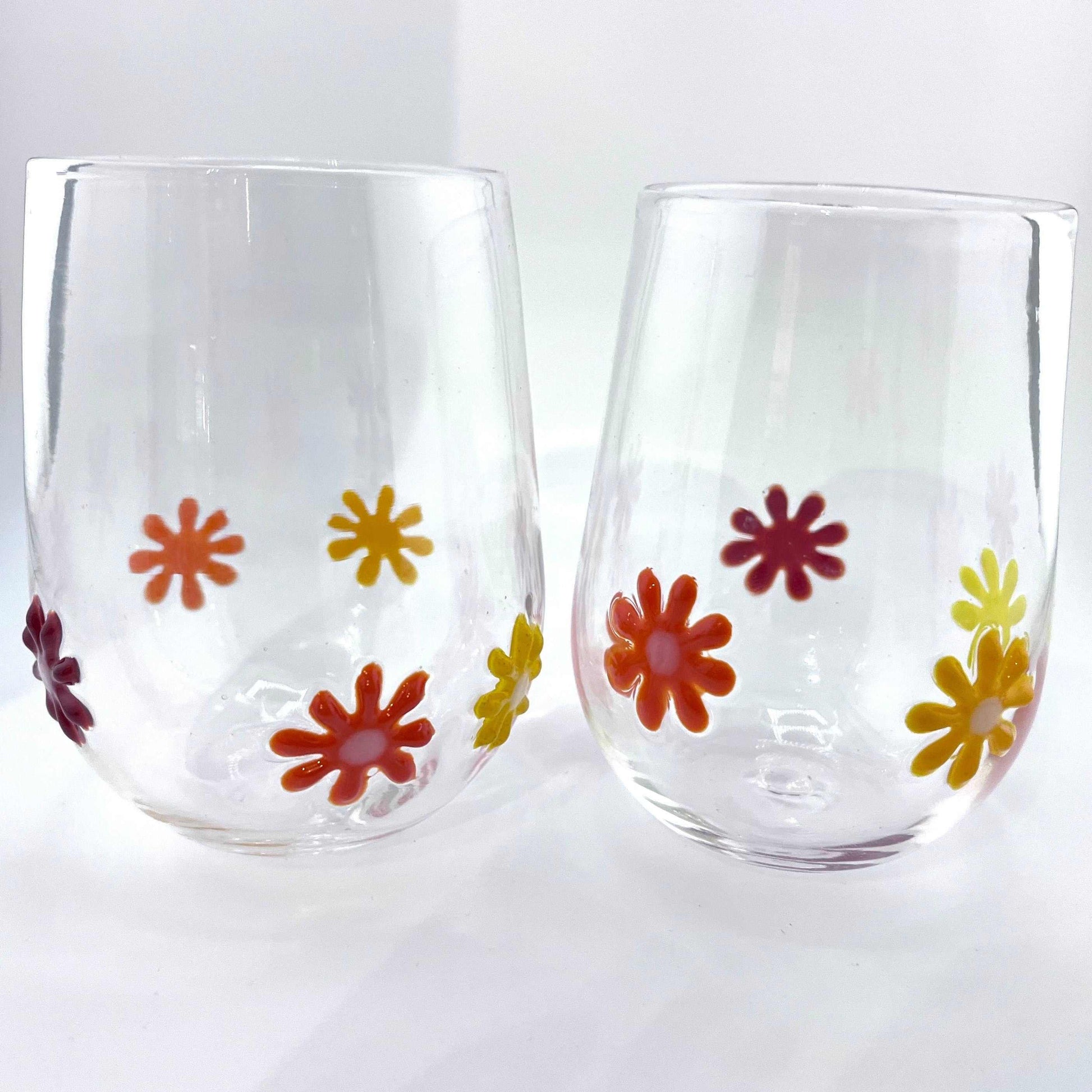 Hand blown Flower Power stemless wine glasses with colorful retro flower designs, 12 oz capacity, dishwasher safe.