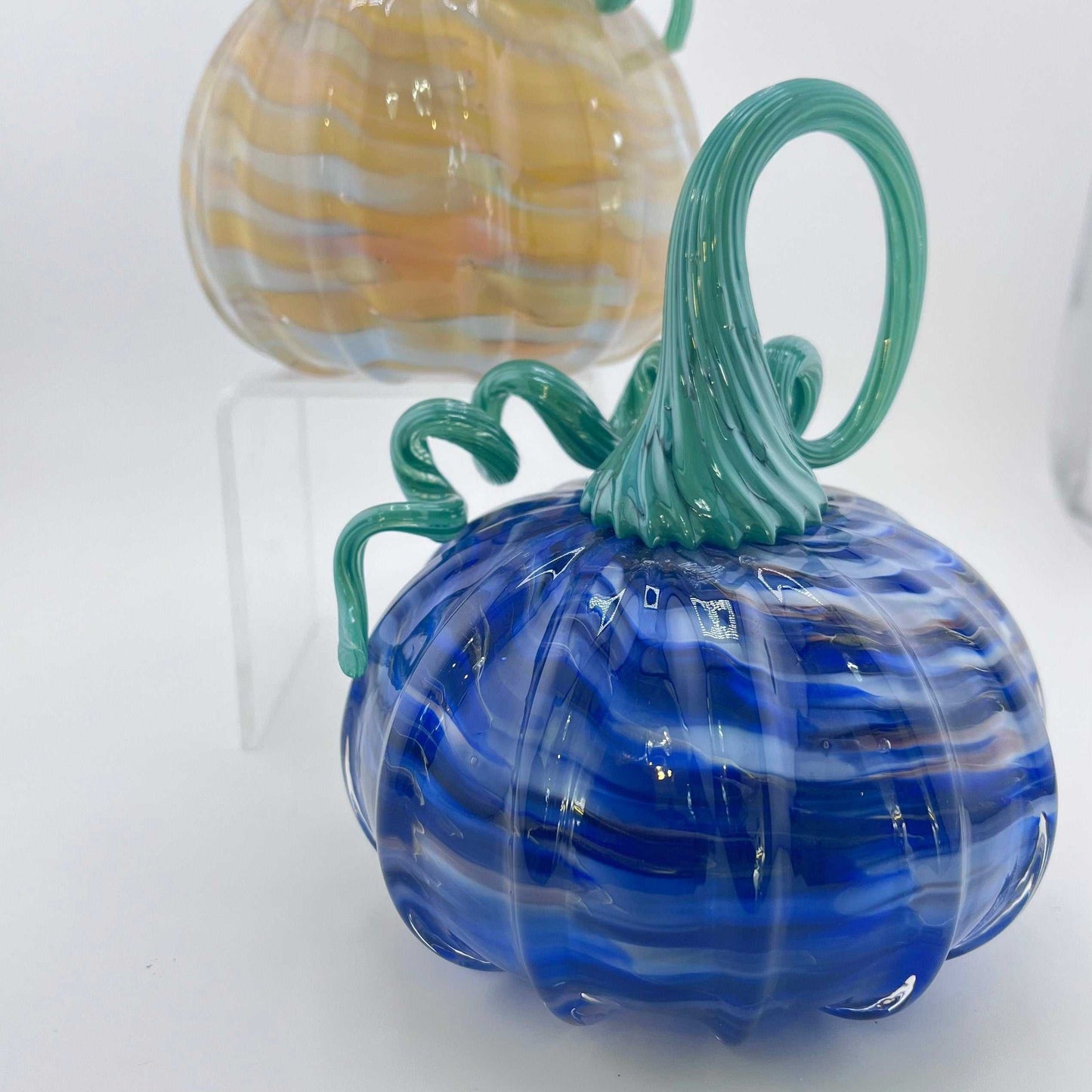 Set of two hand blown swirly glass pumpkins with curly green stems, one blue and one amber, handmade and signed.