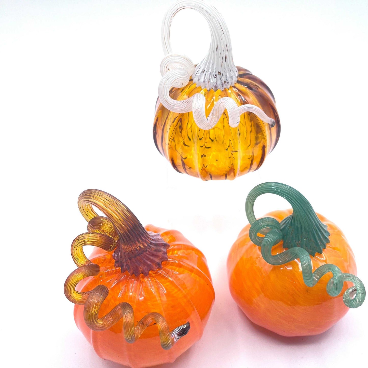 Set of three hand blown glass pumpkins with curly stems in orange and amber tones, each signed and dated, handcrafted by Blackstone River Glass Center.