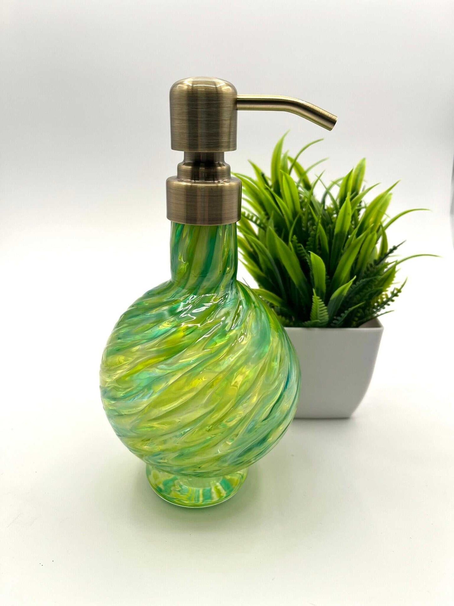 Marbled glass vanity soap dispenser in emerald and olive with brushed metal pump, handcrafted with a swirl pattern