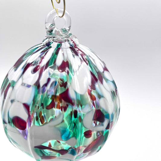 Holiday hand blown glass ornament with multicolored abstract design and gold hanging hook
