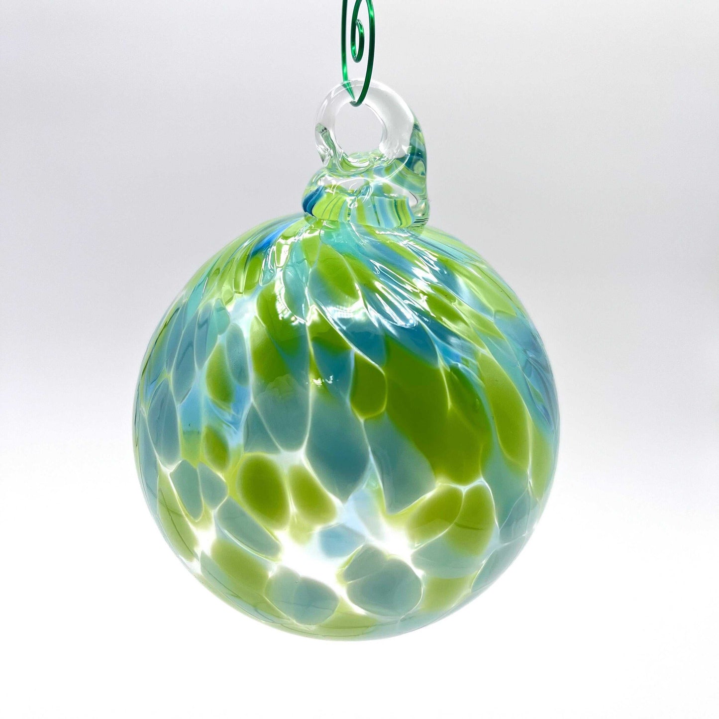 Green speckled hand blown glass ornament with blue and green swirls hanging loop