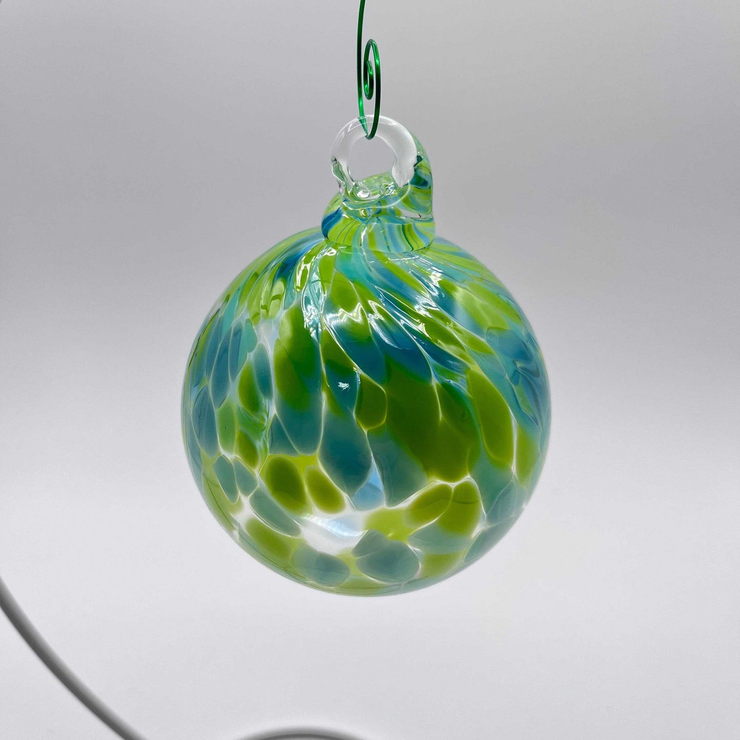 Green speckled hand blown glass ornament hanging with blue and green patterns, 4x4 inches, handcrafted decorative bauble