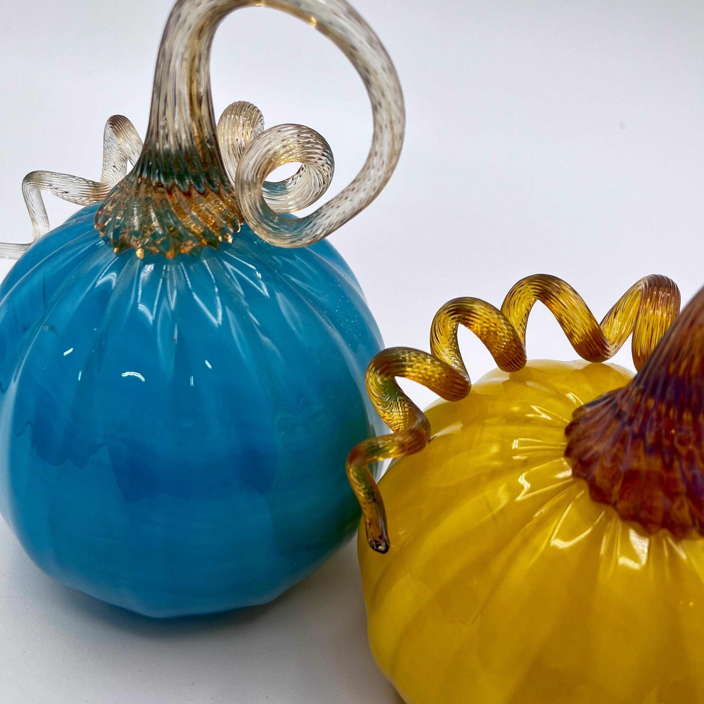Set of two hand blown glass pumpkins with curly stems in blue and yellow colors