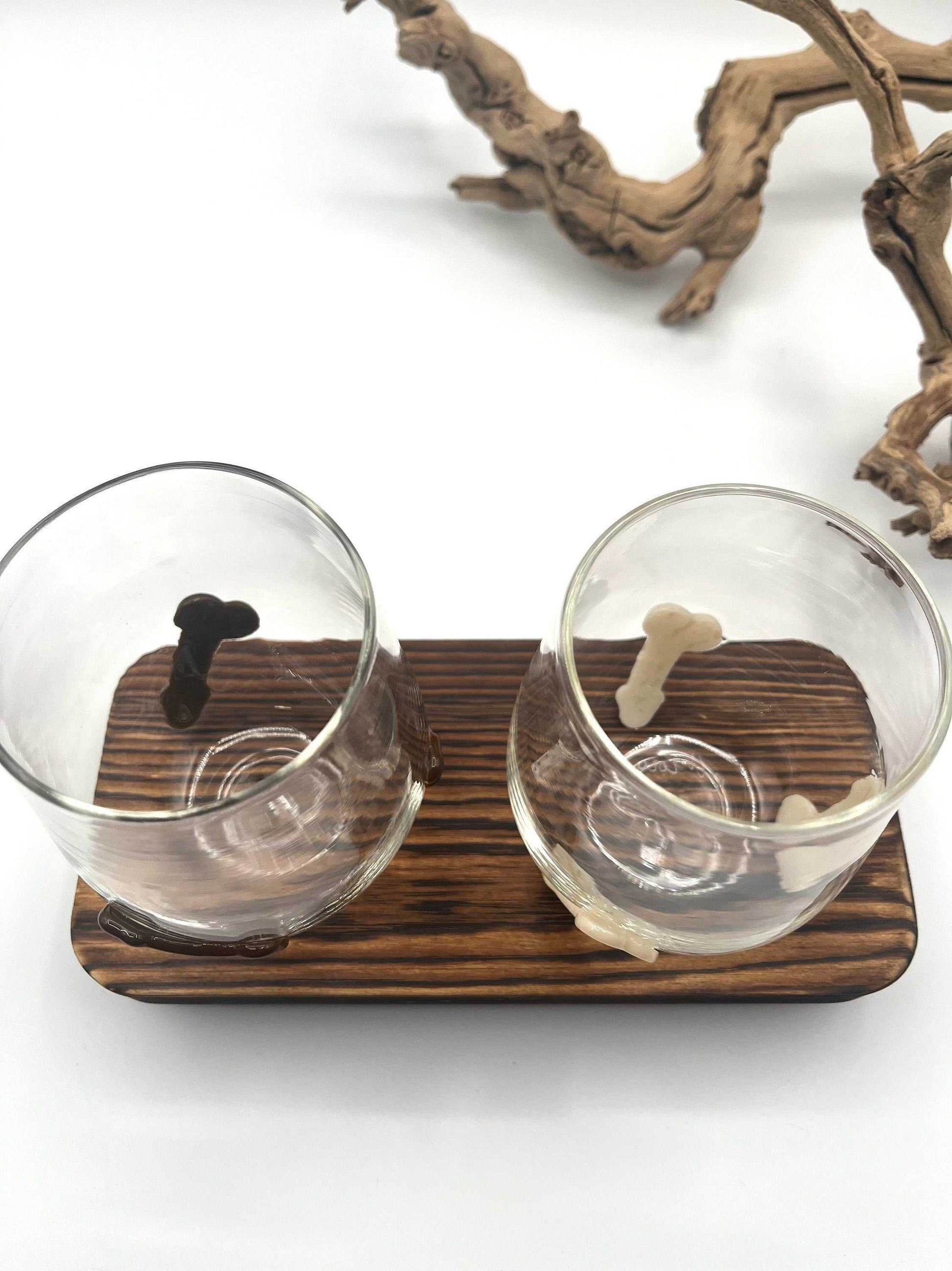 Hand blown stemless wine glasses with chocolate and vanilla penis-shaped handles on wooden tray, novelty party favor cups