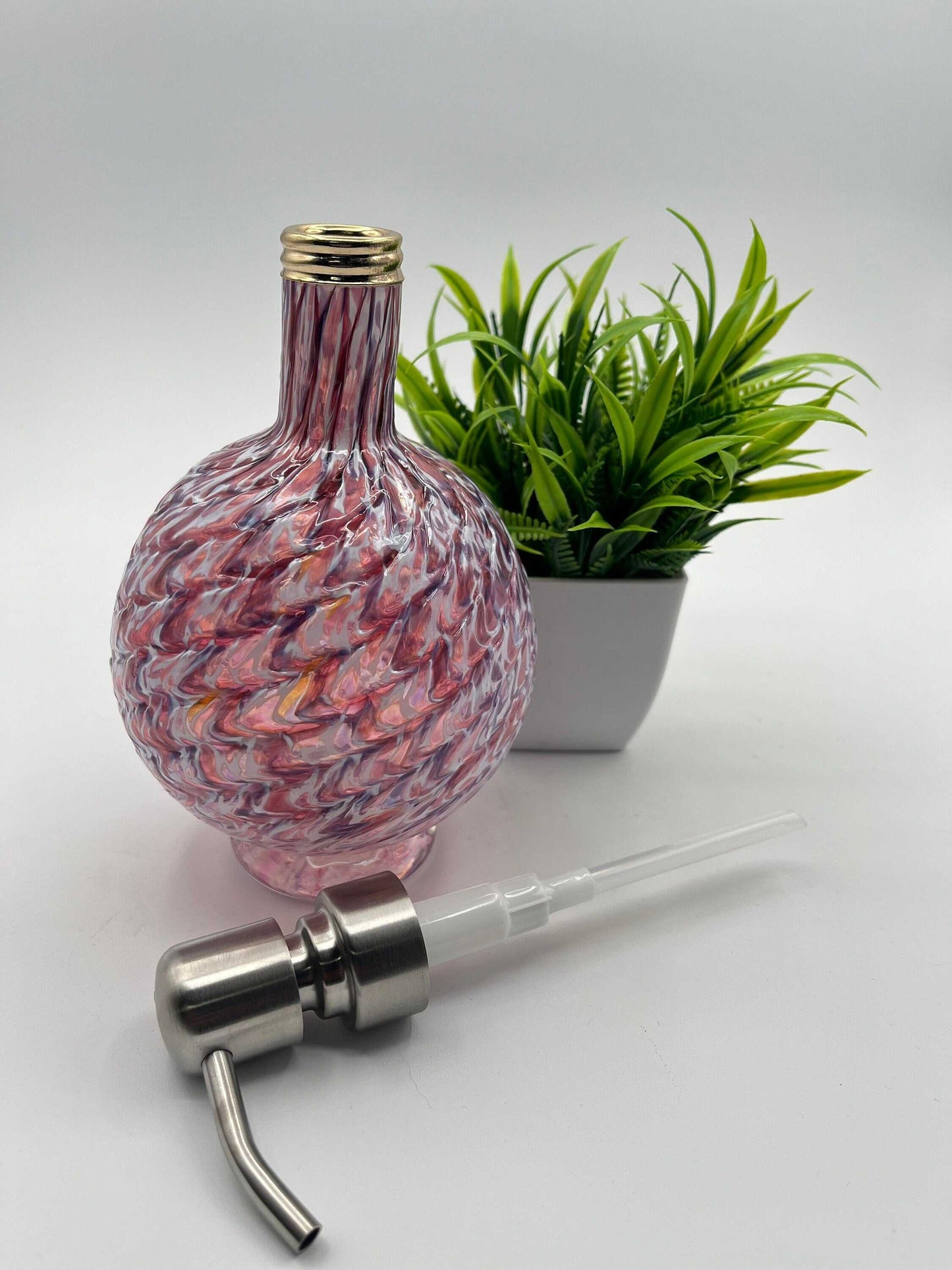RubyAmethyst Mix marbled hand blown glass soap dispenser with metal pump and decorative plant background