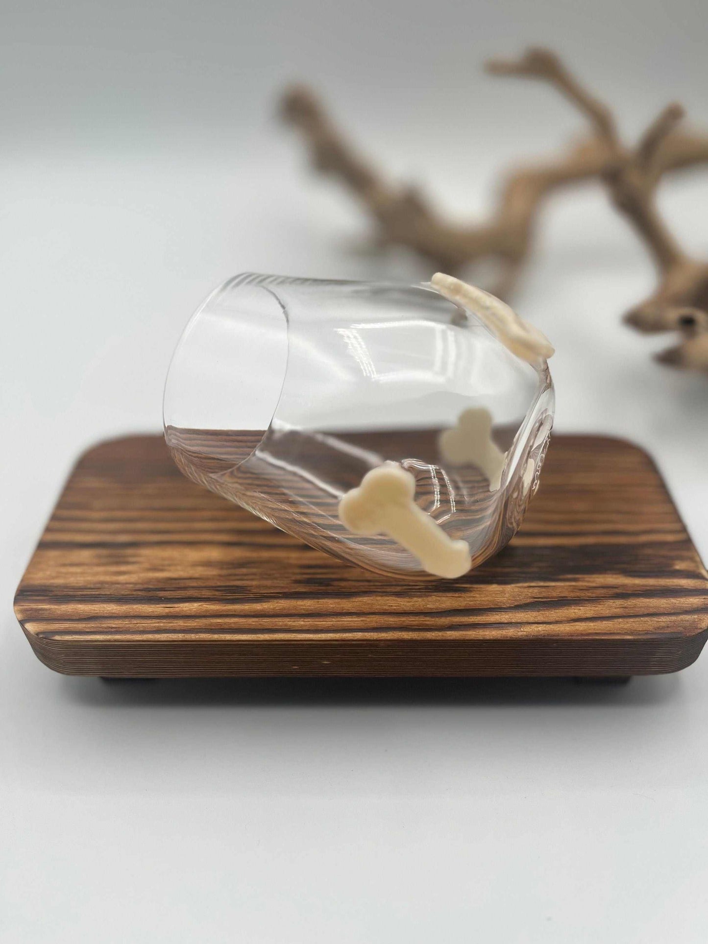 Hand blown stemless wine glass with three small decorative glass shapes on the outside, displayed on a wooden surface.