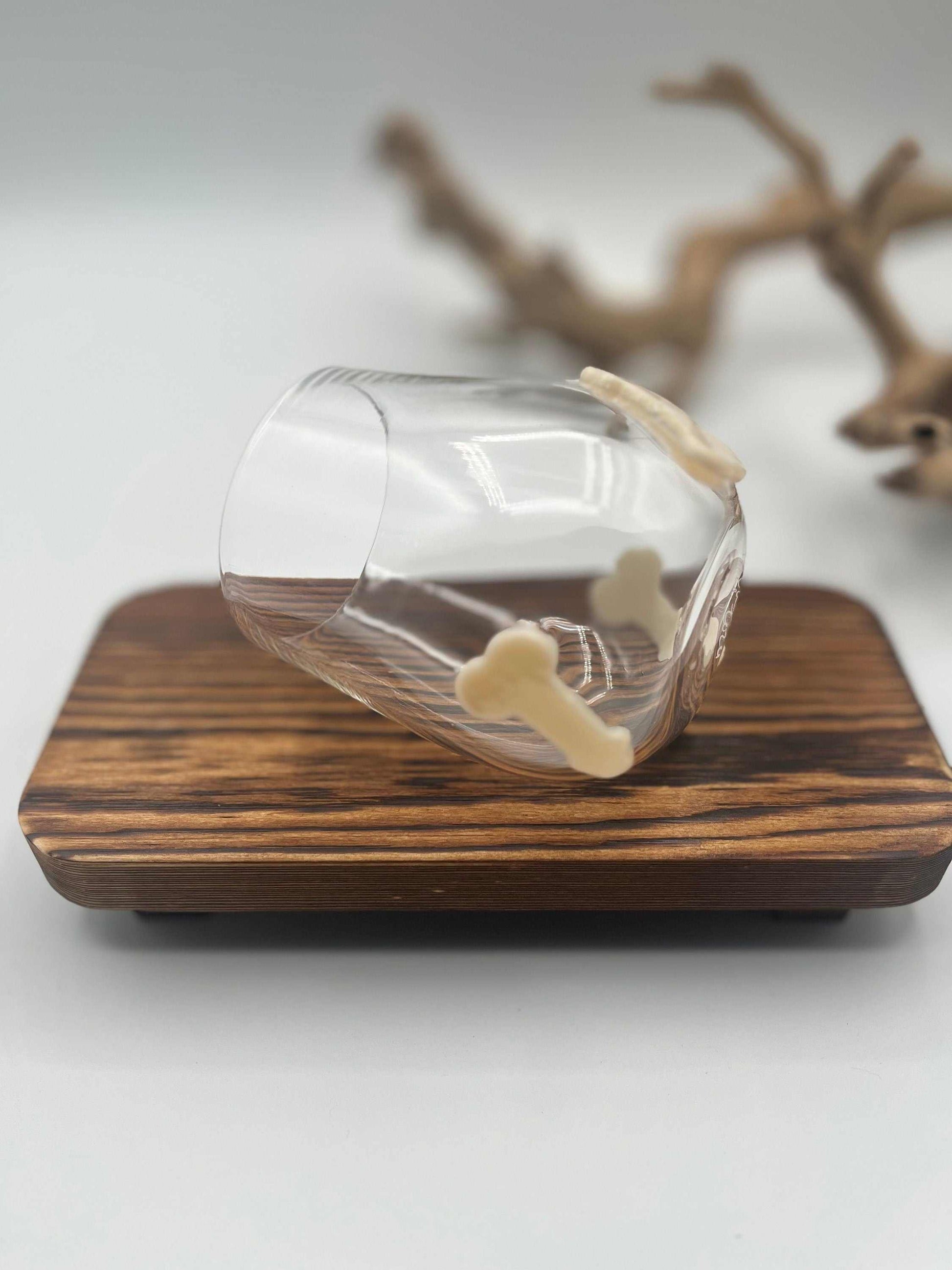 Hand blown stemless wine glass with three small decorative glass shapes on the outside, displayed on a wooden surface.