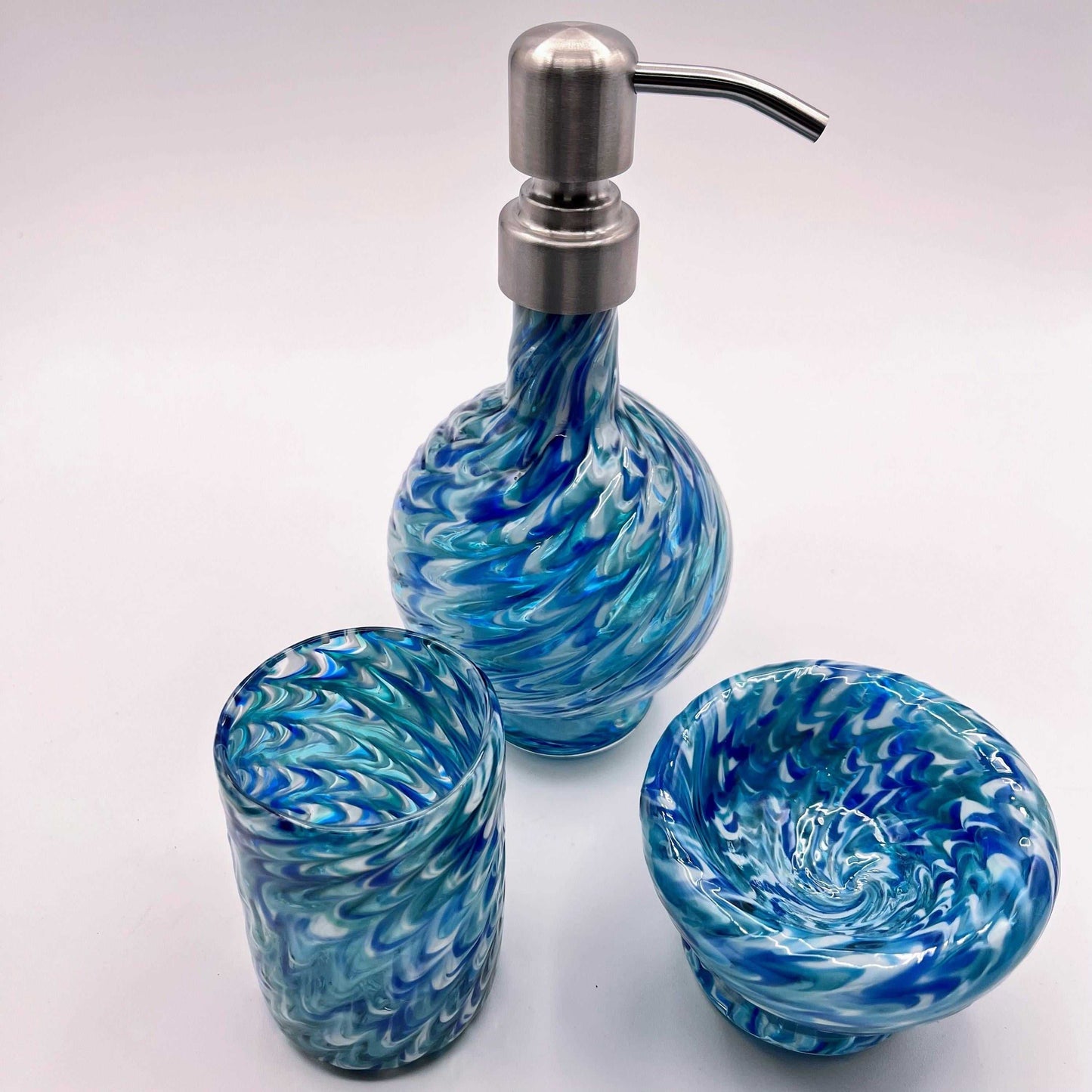 Marbled glass vanity set in ocean blue with hand-blown soap dispenser, matching bowl, and coordinating glass