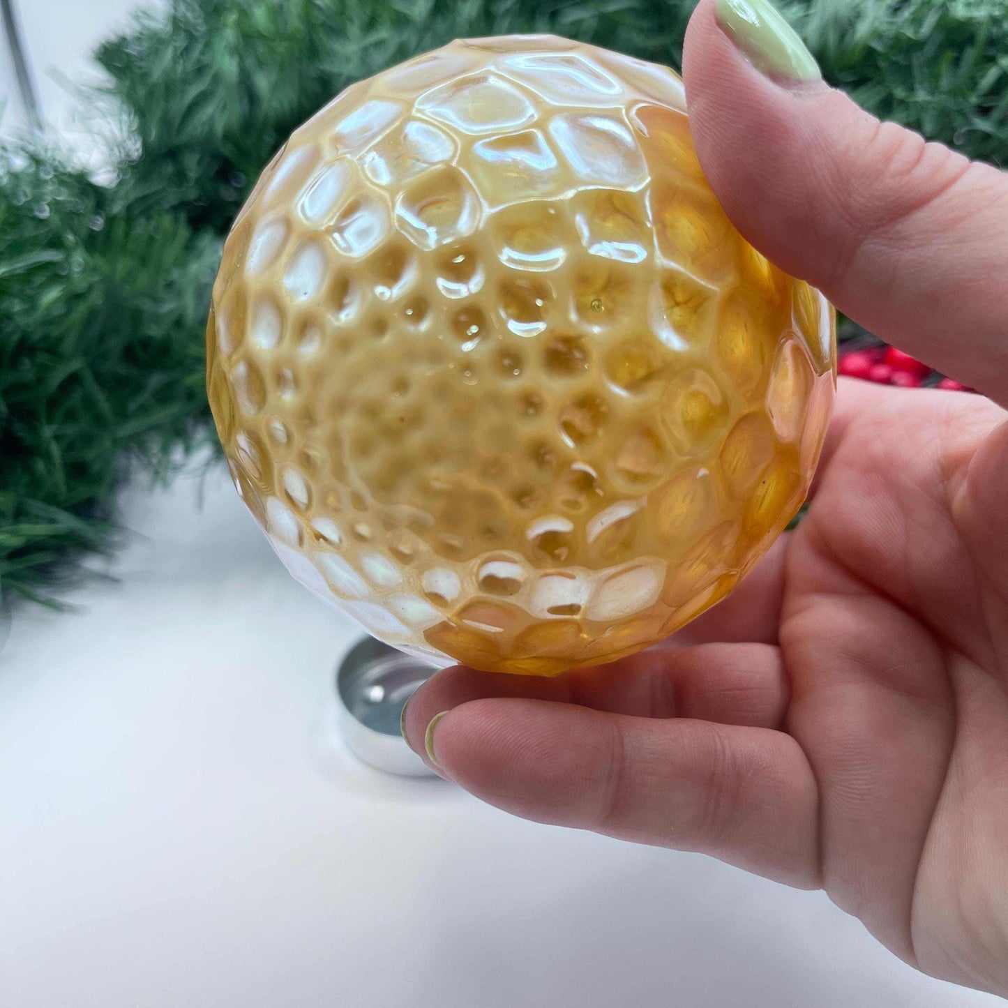 Hand blown Vanilla Gold Diamond glass ornament with textured design held in hand