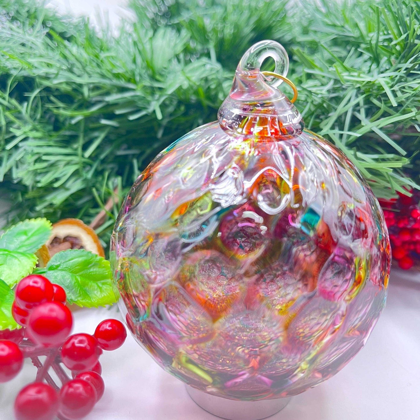 Colorful artisan hand-blown glass ornament with swirled rainbow hues, perfect for holiday decor and gifting.