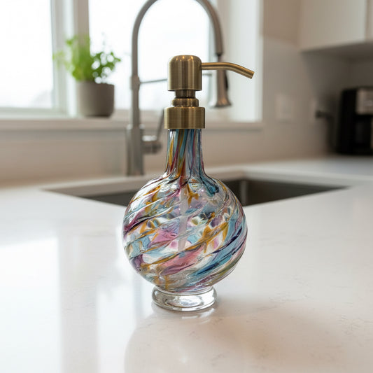 Decorative glass soap dispenser with a metallic pump on a white background