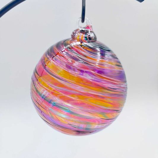 Hand blown Sunset Spiral Twist glass ornament with vibrant swirling colors in a 4x4 inch sphere