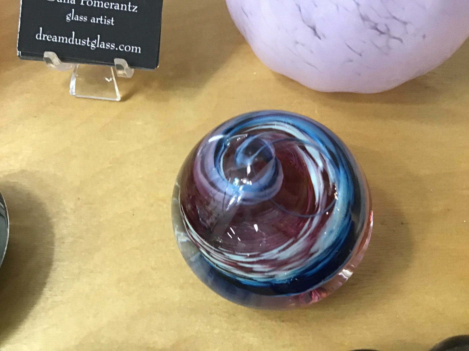 Colorful glass swirl paper weight on wooden surface